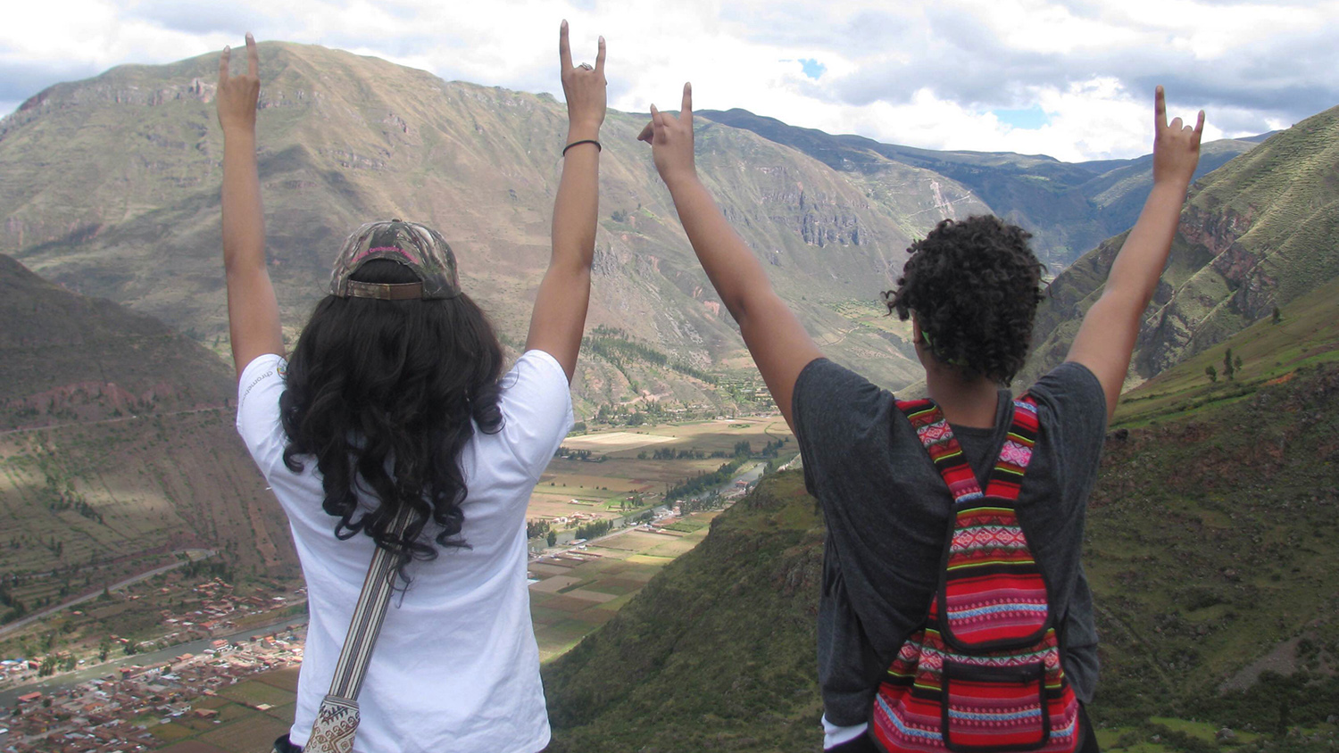 two students hold up wolfies on mountain top