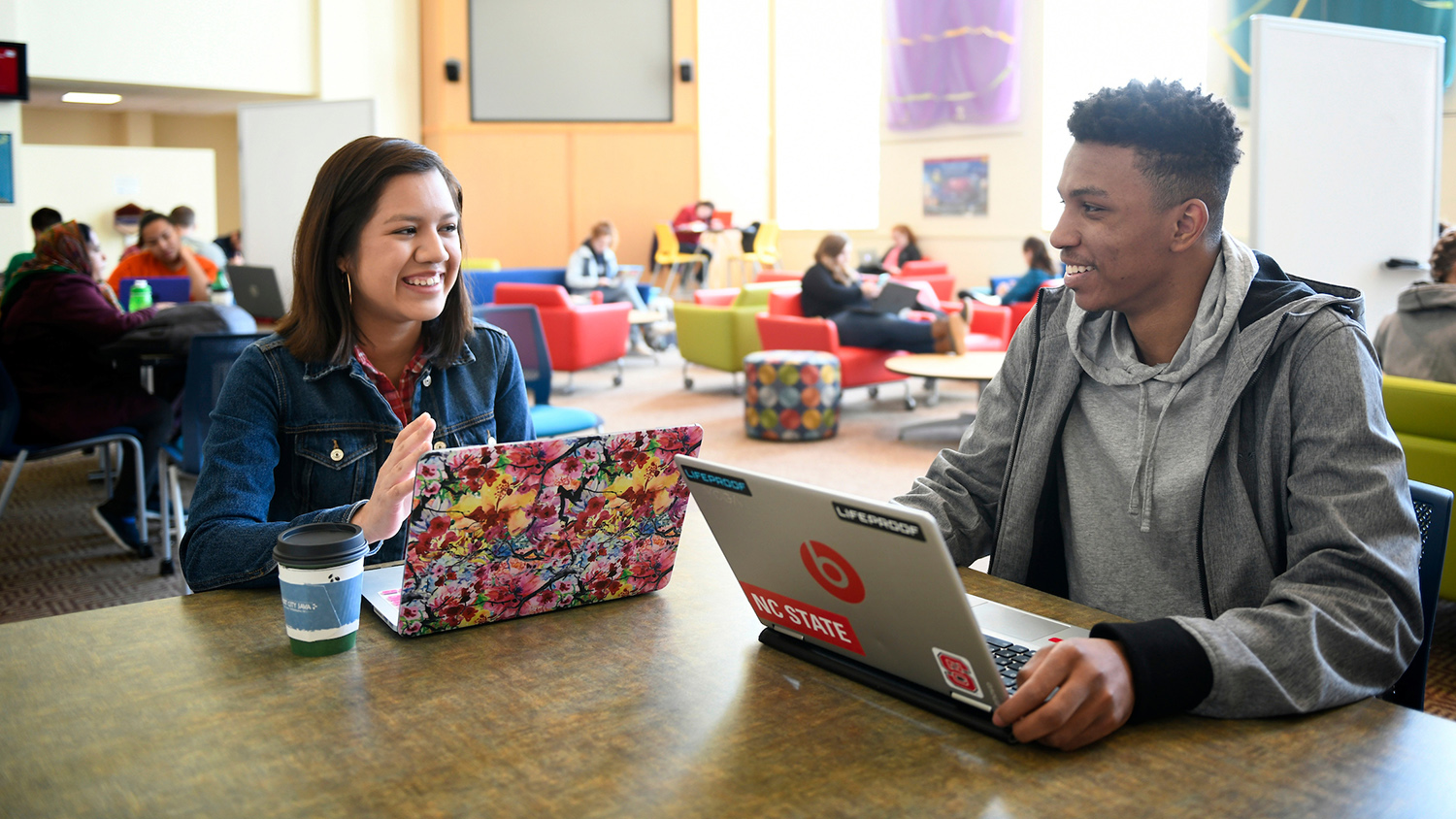 Students talk while working on laptops